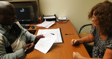 a man and a woman seated at a table discussing documents together