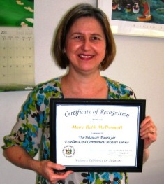 Photo of MaryBeth McDermott holding up the Governor's Award for Excellence and Commitment in State Service